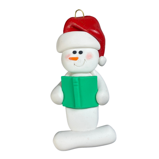 Ornament of white snowman in red hat holding a green book.