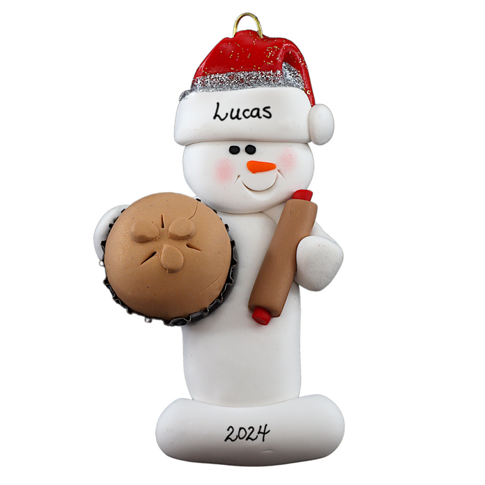 Ornament of white snowman in red hat holding a baked pie and rolling pin, personalized with name.