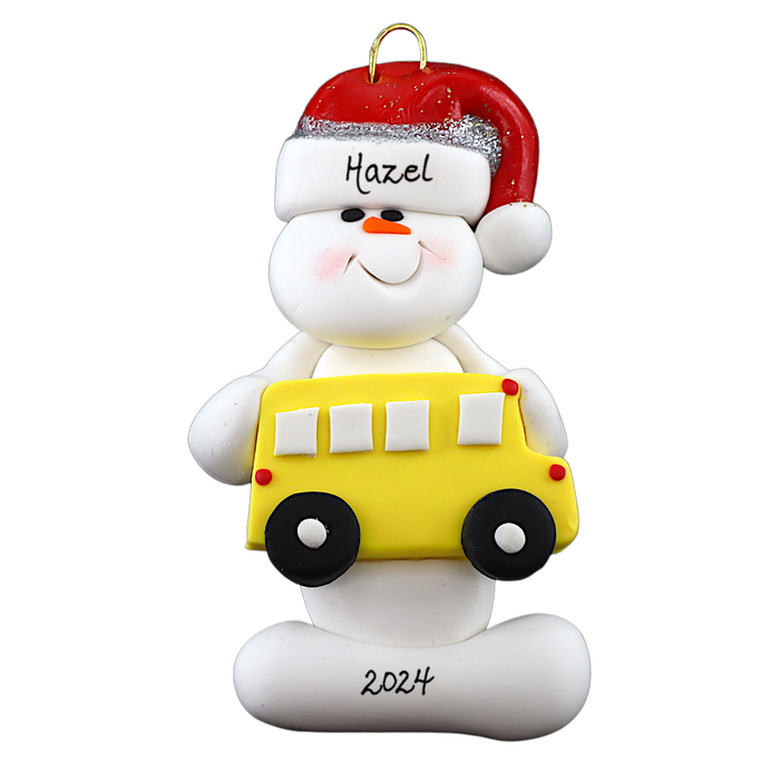 Ornament of white snowman in red hat holding a yellow school bus, personalized with name.