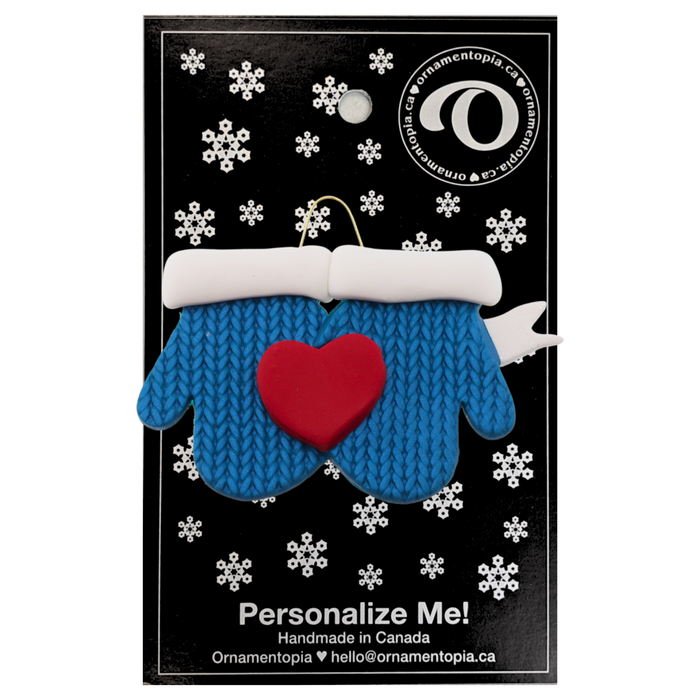 A couple’s ornament of two mittens cradling a heart, on display backing card.