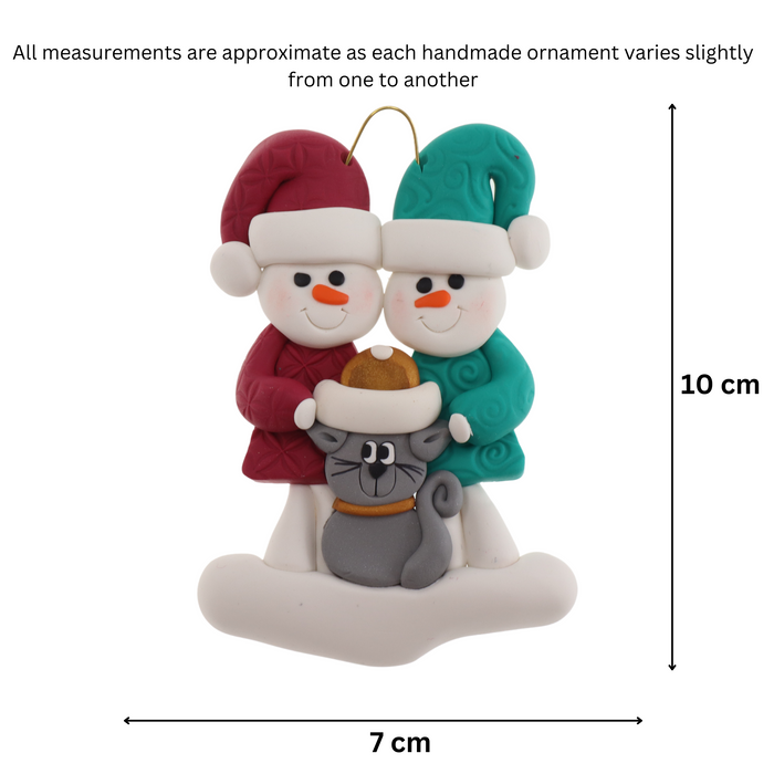 Ornament of snowman couple in red and green shirts and hats with grey cat in Christmas hat, graphed to show size (7x10cm).