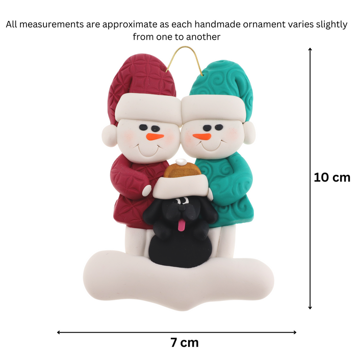 Ornament of snowman couple in red and green shirts and hats with black dog in Christmas hat, graphed to show size (7x10cm).
