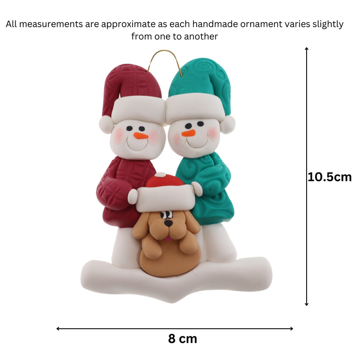 Ornament of snowman couple in red and green shirts and hats with tan dog in Christmas hat, graphed to show size (8x10.5cm).