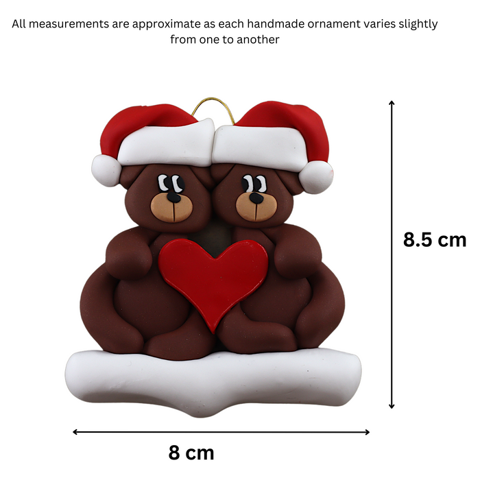 A couple’s ornament of two brown bears holding a red heart together, graphed to show size (8x8.5cm).