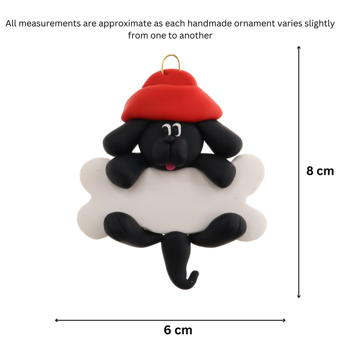 Ornament of black dog in red hat hanging on a white bone, graphed to show size (6x8cm).