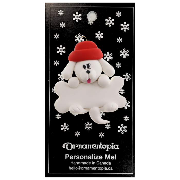 Ornament of white dog in red hat hanging on a white bone, on display backing card.