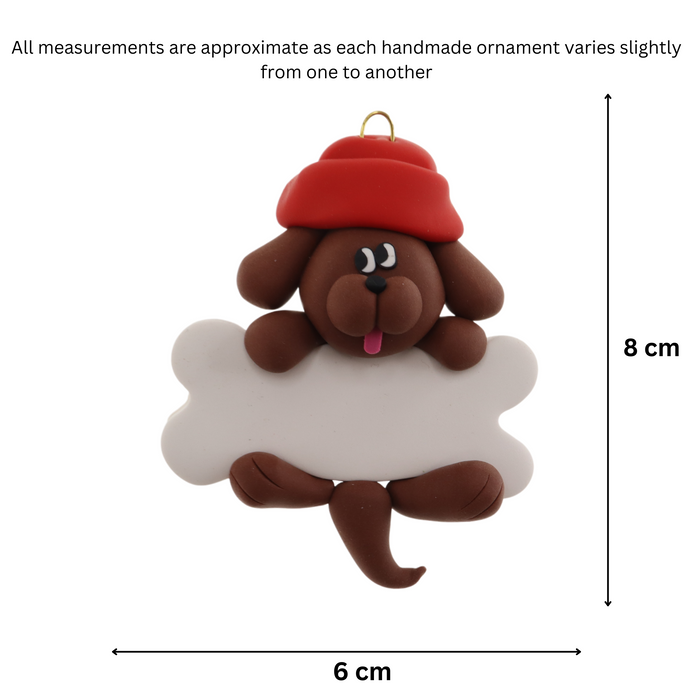 Ornament of brown dog in red hat hanging on a white bone, graphed to show size (6x8cm).