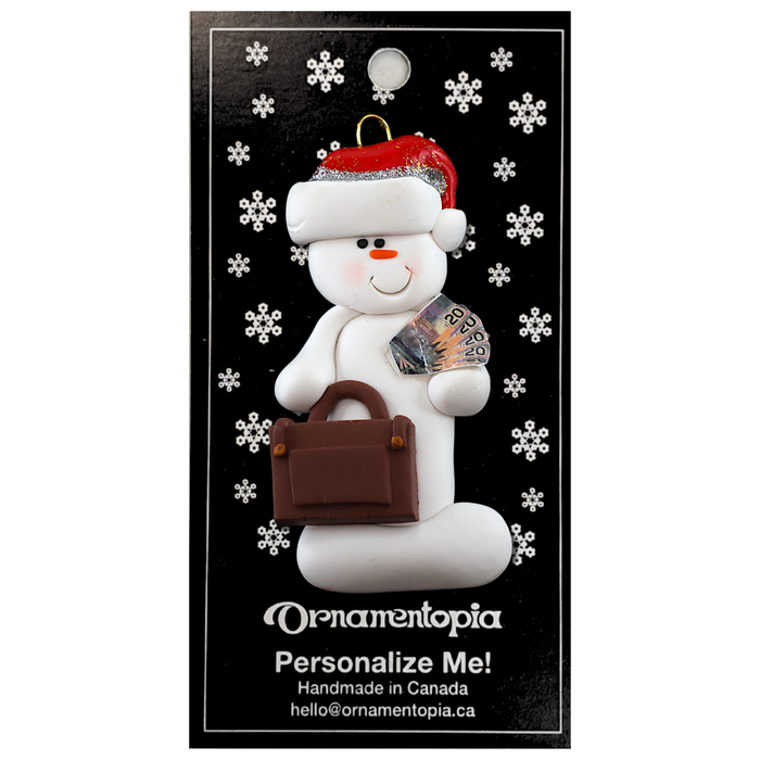 Ornament of white snowman in red hat holding a briefcase and paper bills, on display backing card.