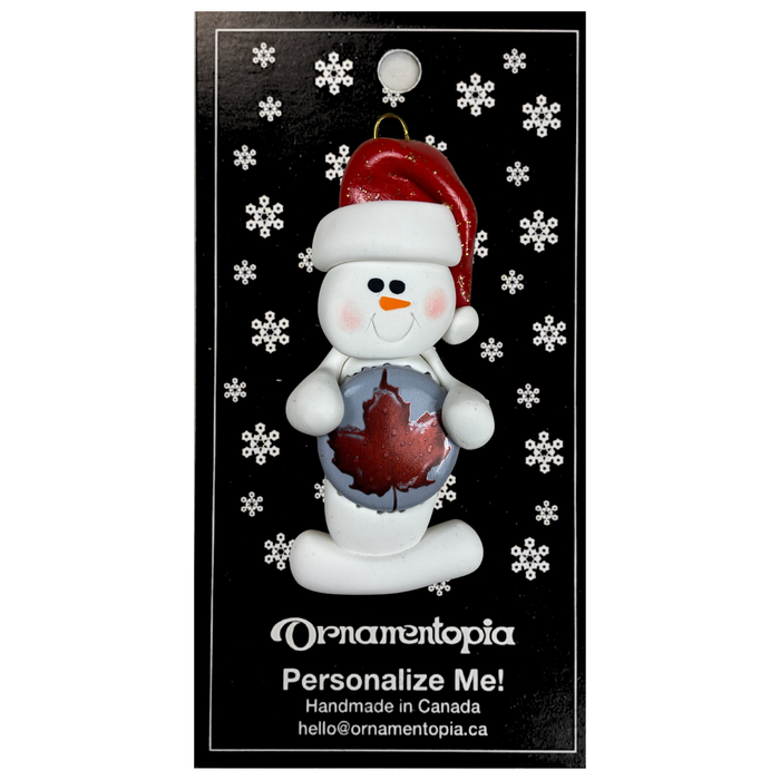 Ornament of white snowman in red hat holding a beer bottle cap, on display backing card.
