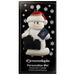 Ornament of white snowman in red hat holding a passport and suitcases, on display backing card.