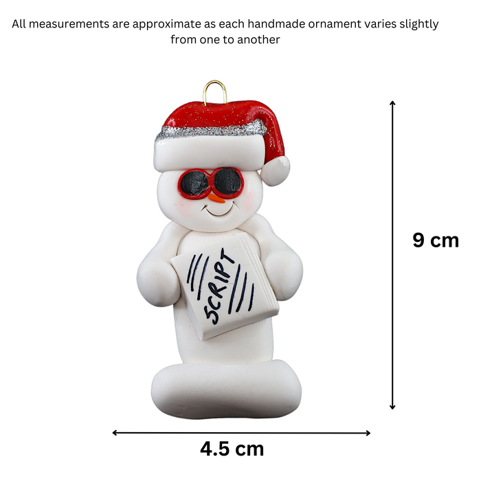 Ornament of white snowman in red hat and sunglasses holding a movie script, graphed to show size (4.5x9cm).