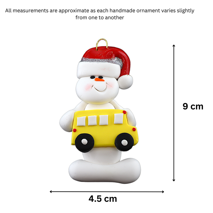 Ornament of white snowman in red hat holding a yellow school bus, graphed to show size (4.5x9cm).
