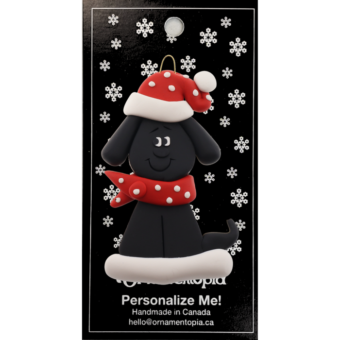 Ornament of black dog in a red and white polka dot Christmas hat and scarf, on display backing card.