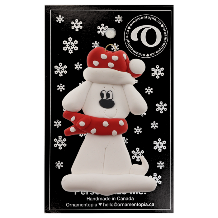 Ornament of white dog in a red and white polka dot Christmas hat and scarf, on display backing card.