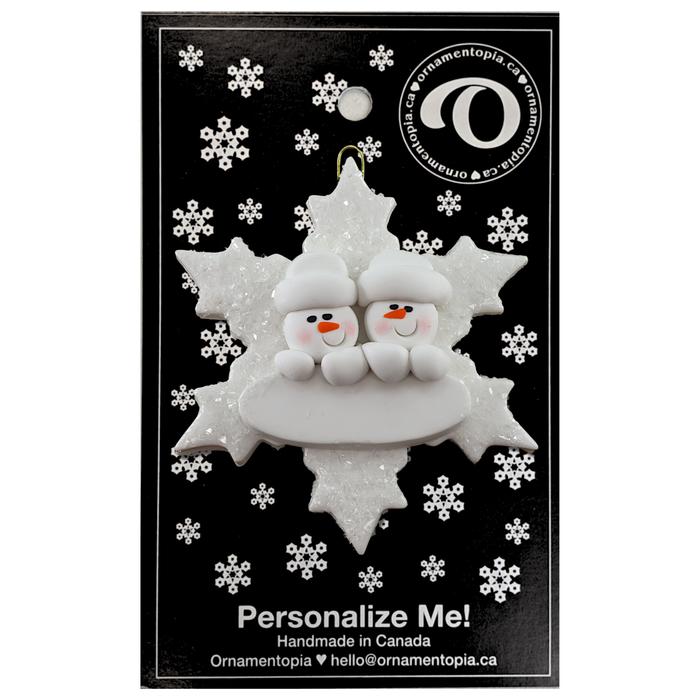 Family ornament with 2 white snowmen stacked on top of a glitter white snowflake, on display backing card.