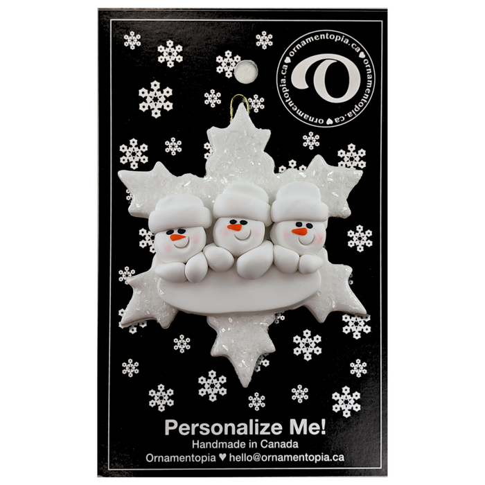 Family ornament with 3 white snowmen stacked on top of a glitter white snowflake, on display backing card.