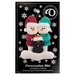 Ornament of snowman couple in red and green shirts and hats with black dog in Christmas hat, on display backing card.