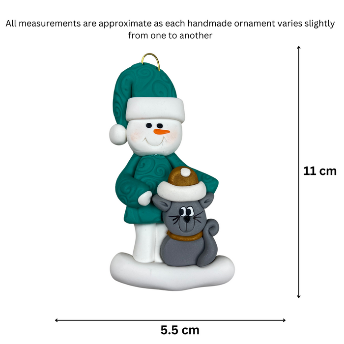 Ornament of snowman in a green shirt and hat with grey cat in Christmas hat, graphed to show size (5.5x11cm).
