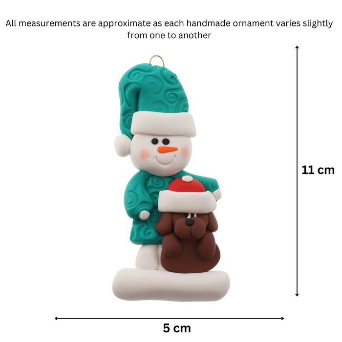 Ornament of snowman in green shirt and hat with brown dog in Christmas hat, graphed to show size (5x11cm).