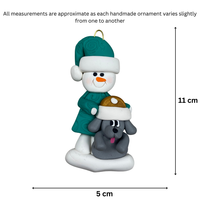 Ornament of snowman in green shirt and hat with grey dog in Christmas hat, graphed to show size (5x11cm).
